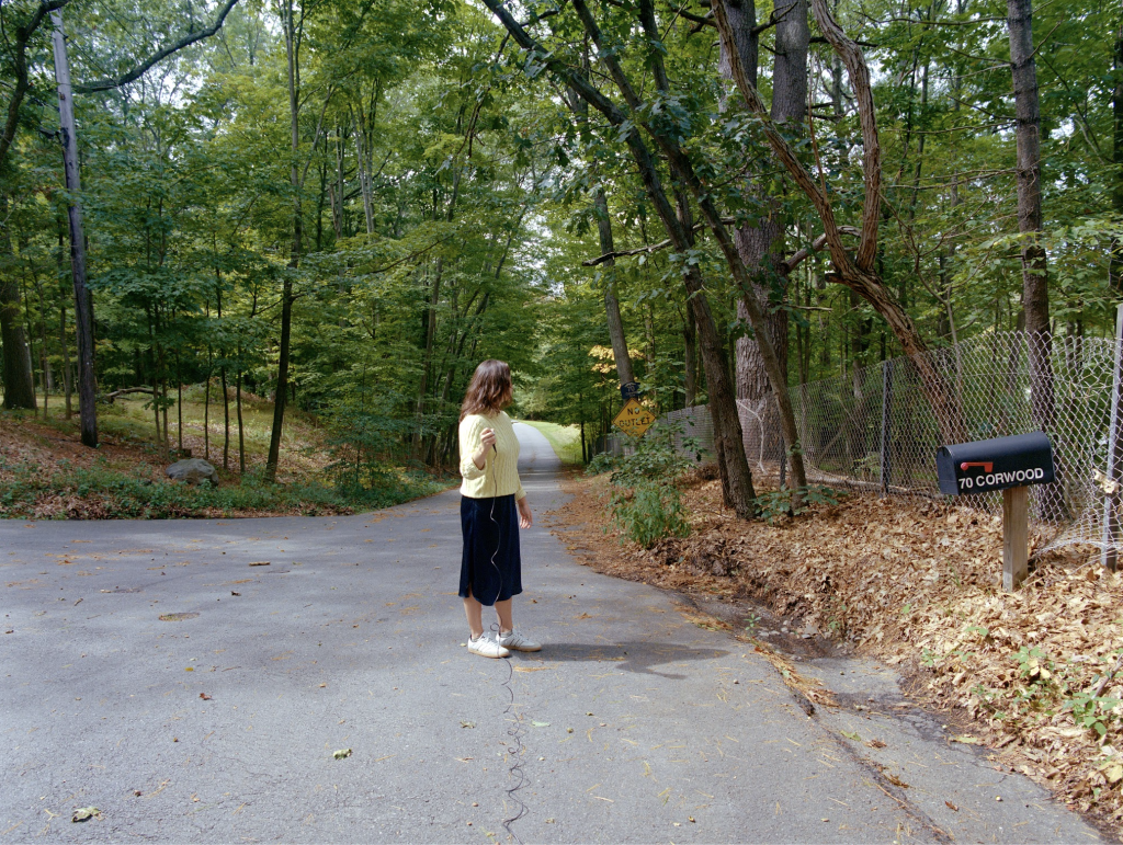 Girl standing in the middle of a road surrounded by trees
