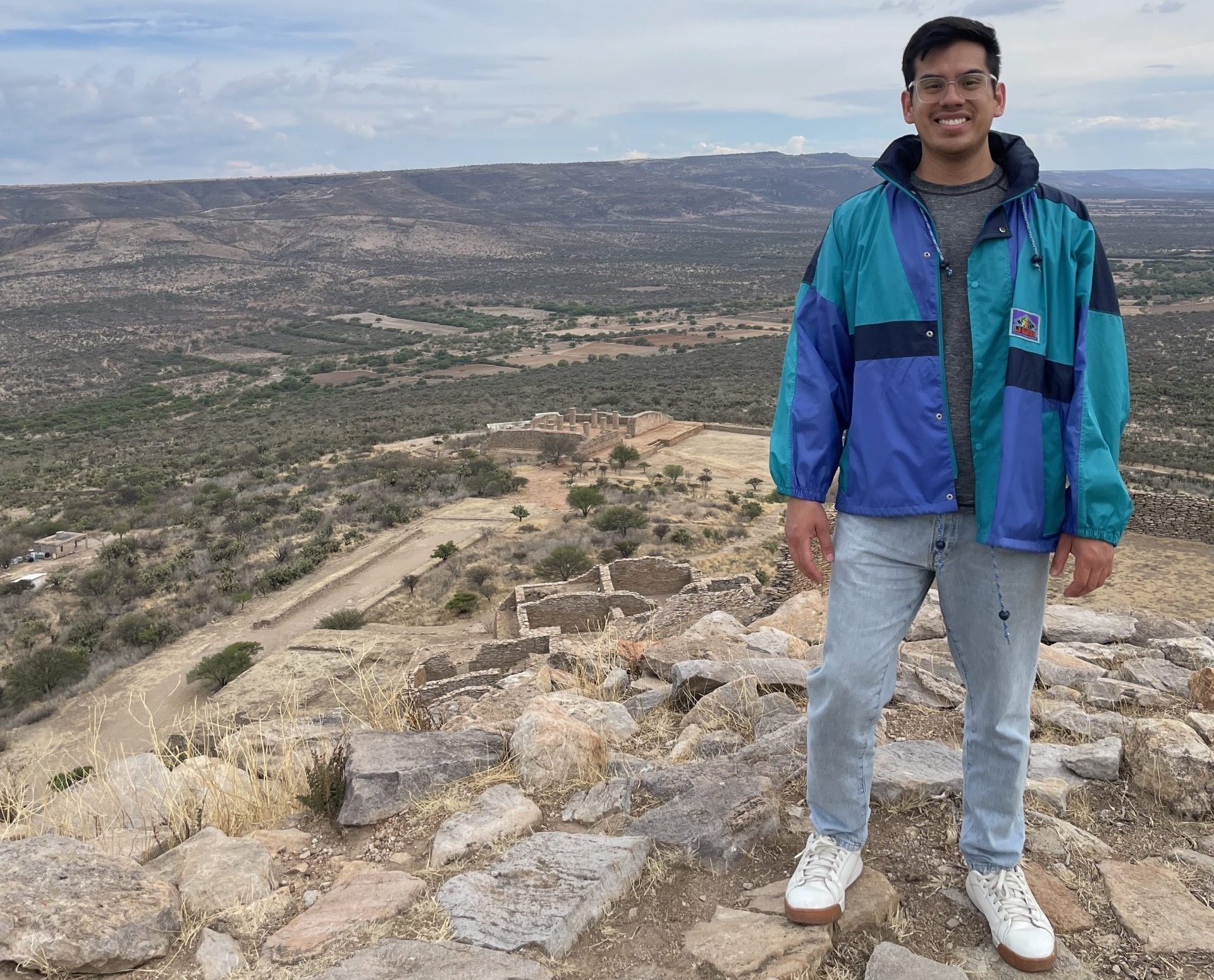 Young man with olive skin and dark brown hair on top of a hill