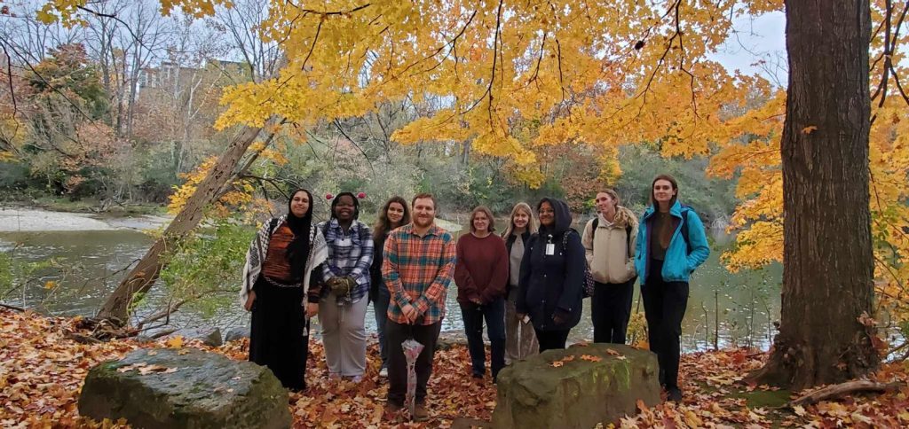 A group of young people posing in front of a tree with yellow foliage
