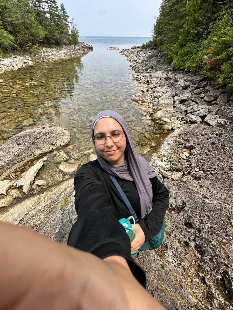 Woman wearing hijab taking a selfie in front of a river